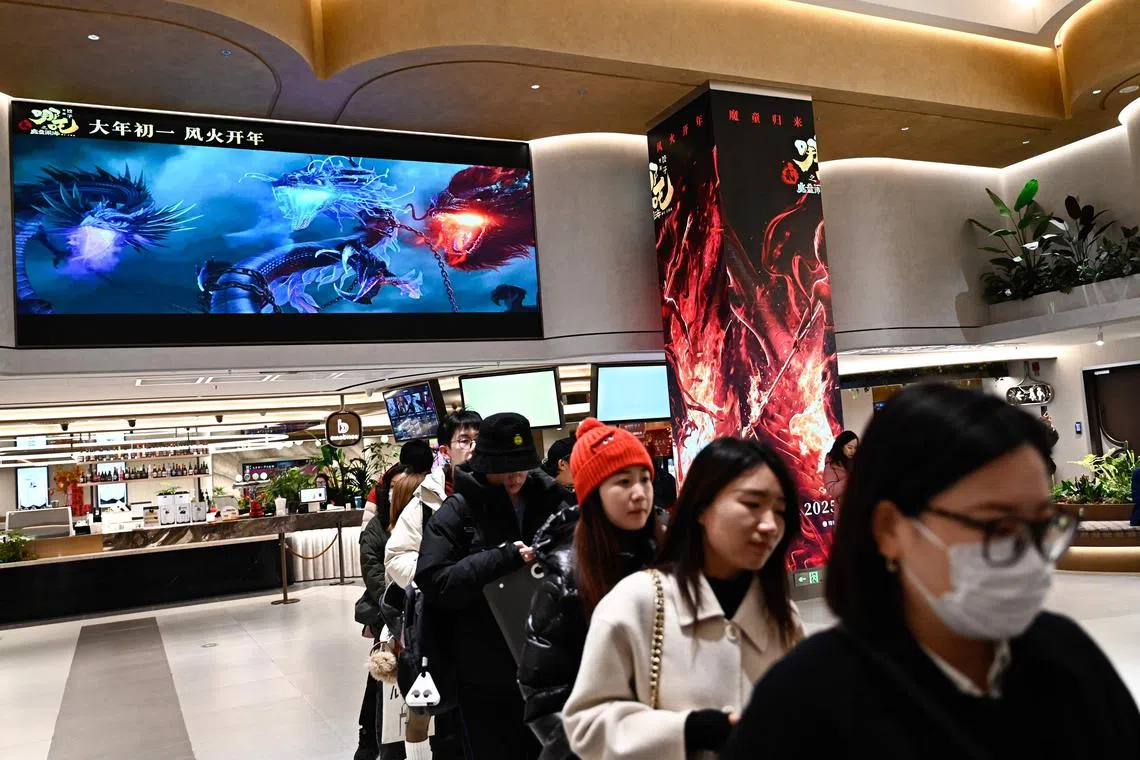 People queue as a screen shows scenes from the animated film Ne Zha 2 at a movie theatre in Beijing on Feb 16, 2025.