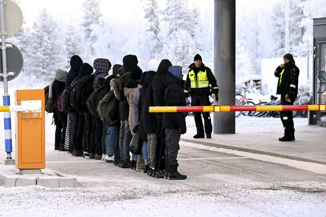 Migrants stand in a line in front of Finnish border guards at the Salla border crossing with Russia, in northern Finland.