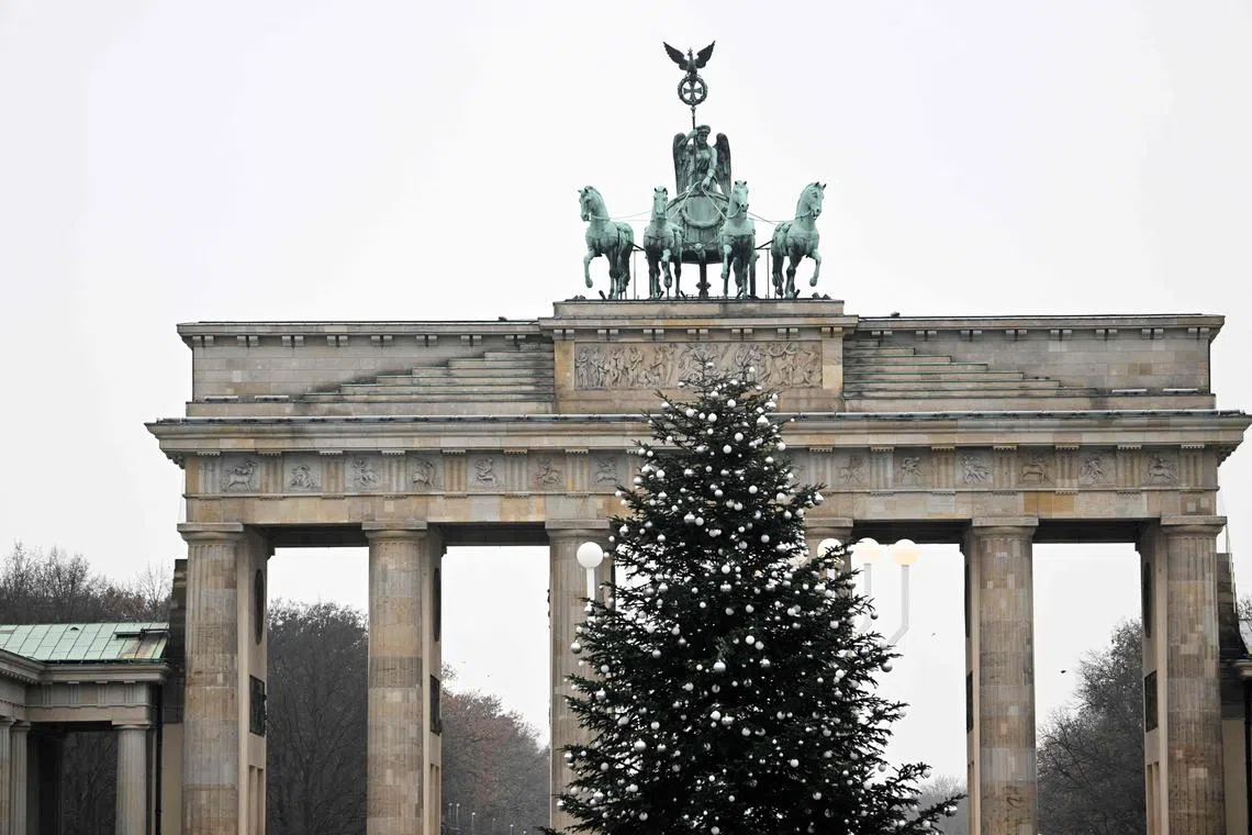 A Christmas tree with its top chopped off is seen in front of Berlin's landmark the Brandenburg Gate on Dec 21, 2022. 