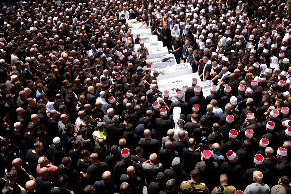 Druze elders and mourners surround the coffins of 10 of the 12 people killed in a rocket strike from Lebanon. 