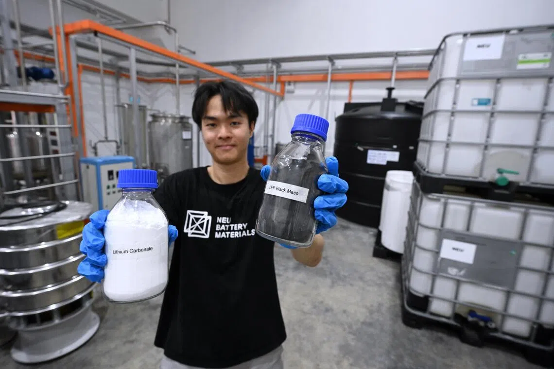 NEU Battery Materials chemical engineer Kek Yi Qiang with a bottle of LFP black mass (right) and a bottle of the finished product lithium carbonate.