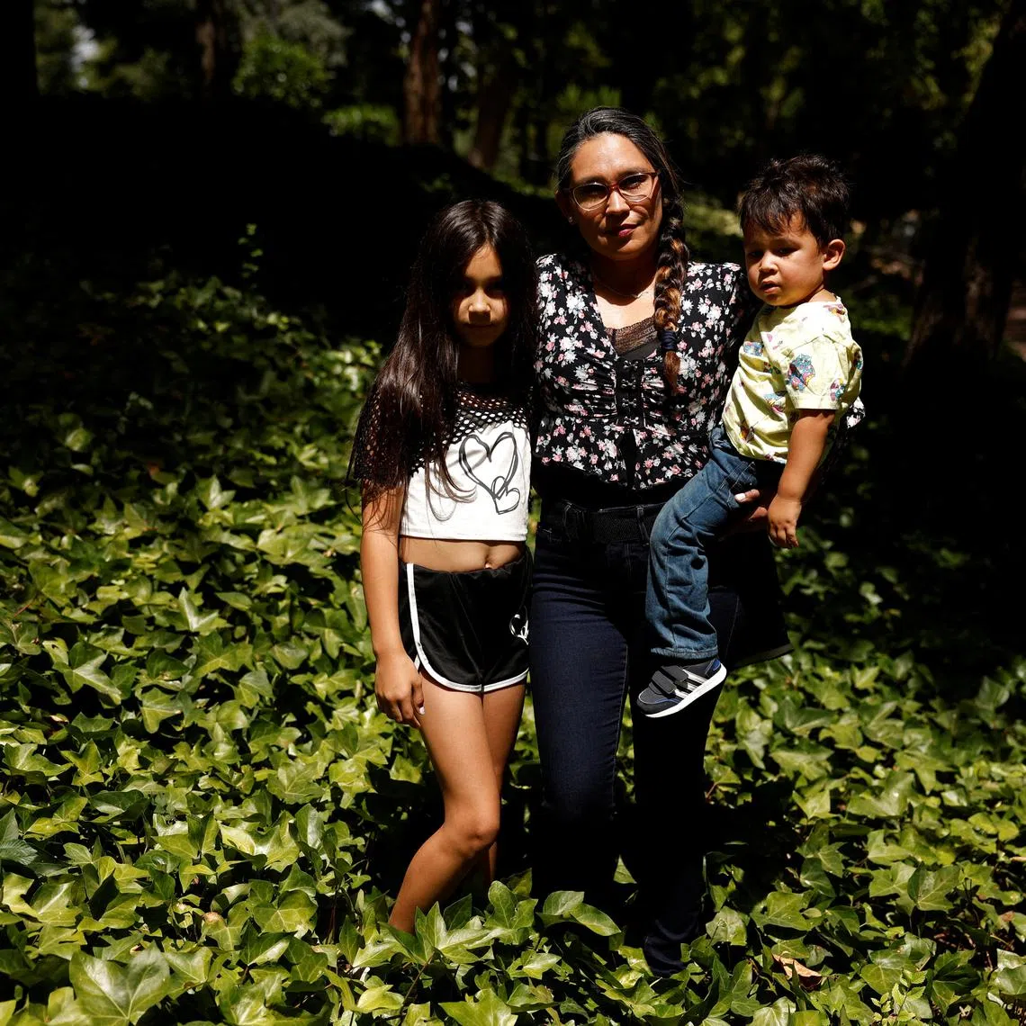 Meliana Bruguera, 41, poses with her children Victoria, 9, and Rurik, 2, before an interview with Reuters in Alcorcon, outside Madrid, Spain August 8, 2025. REUTERS/Susana Vera