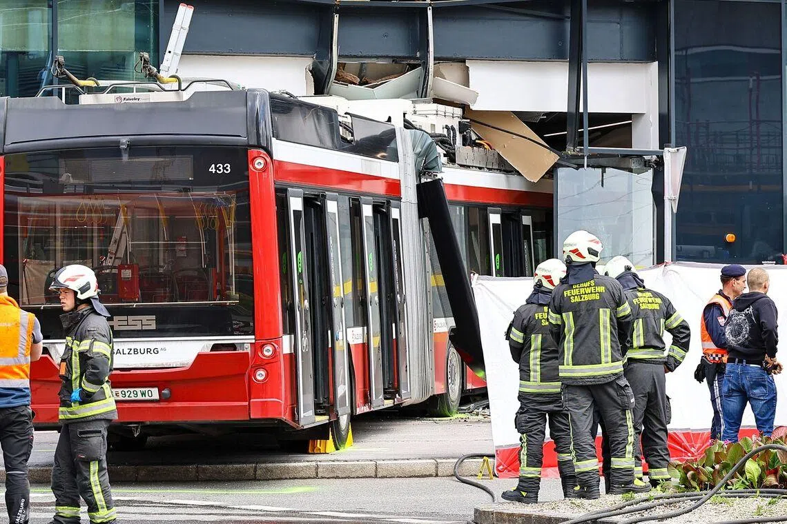 Firefighters and rescue personnel work next to a trolleybus that crashed into a supermarket in Salzburg, Austria, on April 20.