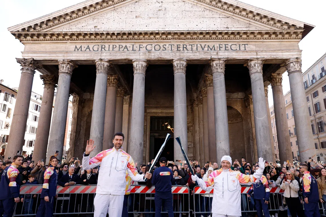Olympics - 2026 Milano-Cortina Winter Olympics - 2026 Milano-Cortina Winter Olympics Torch Relay - Rome, Italy - December 6, 2025  Former basketball player Italy's Andrea Bargnani is passed the Olympics flame during the relay as the Pantheon is seen in the background REUTERS/Remo Casilli