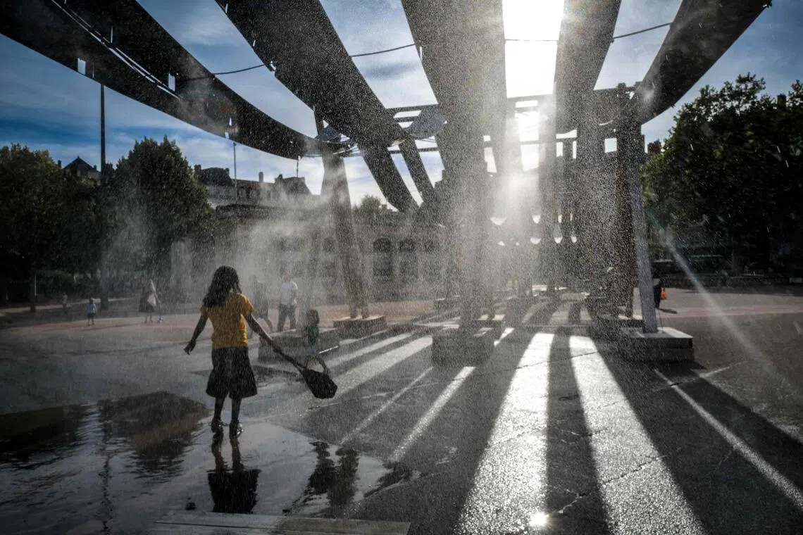 Pedestrians walk through water sprays on Place Bellecour during a heatwave in Lyon, central France.