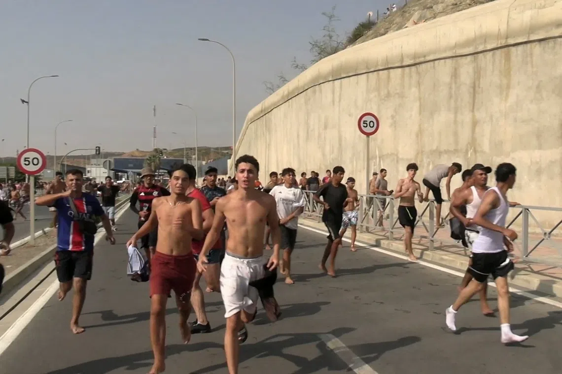 Migrants run and cheer as they cross on foot into the North African enclave of Ceuta from Morocco, on July 310.