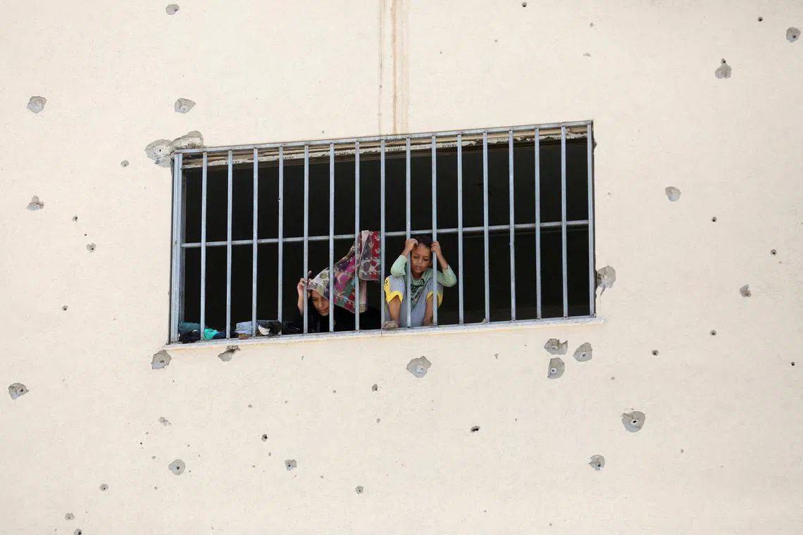 FILE PHOTO: Displaced Palestinians, who fled their houses due to Israeli strikes, look out from a window as they take shelter, amid the ongoing conflict between Israel and Hamas, in Khan Younis in the southern Gaza Strip, July 24, 2024. REUTERS/Hatem Khaled/File Photo