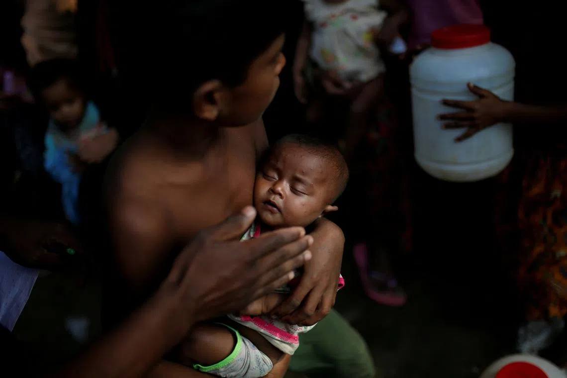 FILE PHOTO: A boy holds a baby as Rohingya refugees wait to receive food supplies at a World Food Programme (WFP) distribution at the Balukhali refugee camp near Cox's Bazar, Bangladesh December 19, 2017. REUTERS/Alkis Konstantinidis/ File Photo