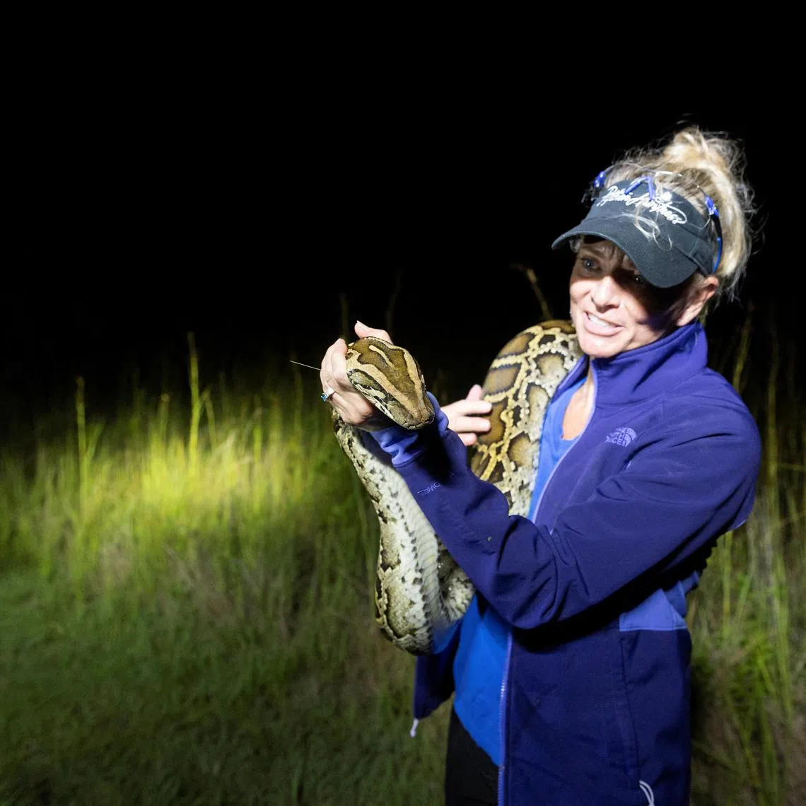 Amy Siewe, a professional hunter of Florida's invasive Burmese python species, holds a python in Ochopee, Florida, U.S. June 6, 2025. REUTERS/Marco Bello