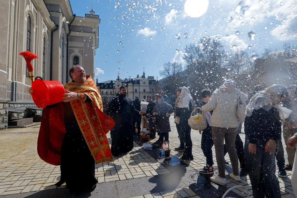 A priest sprays holy water on parishioners outside a cathedral during Orthodox Easter celebrations amid the Russia-Ukraine conflict in Donetsk, a Russian-controlled city of Ukraine, April 12, 2026. REUTERS/Alexander Ermochenko