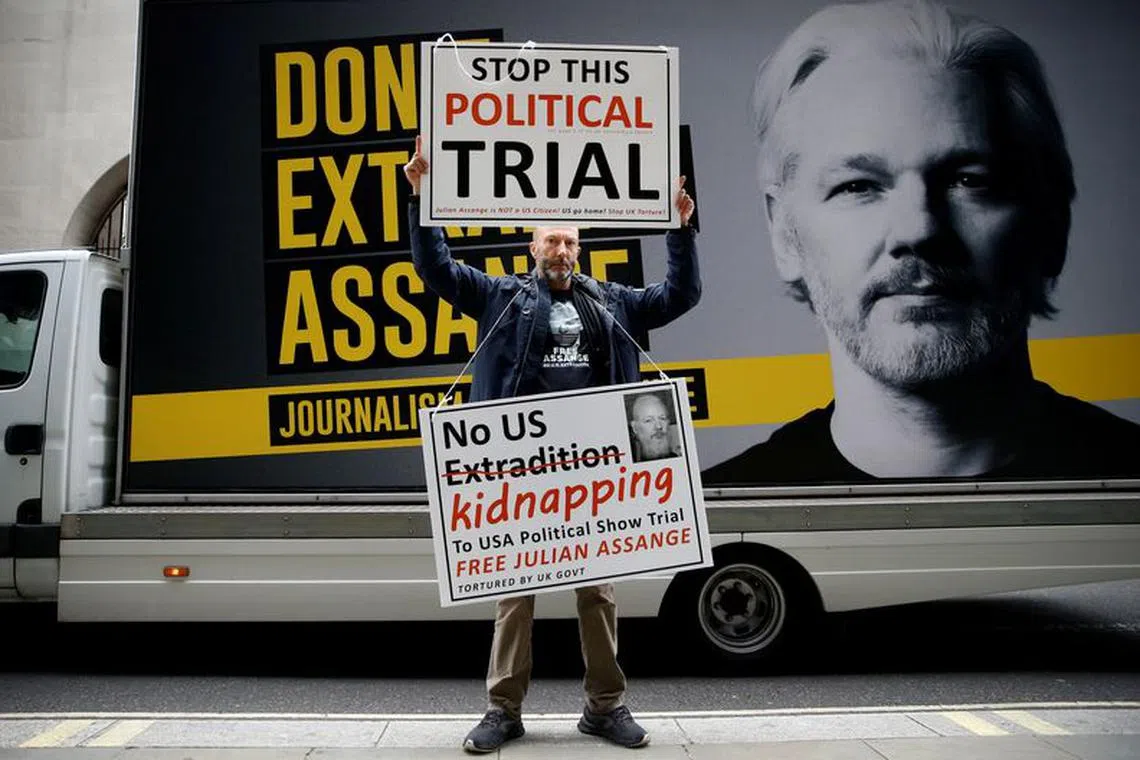 A protestor holds signs outside the Old Bailey, the Central Criminal Court ahead of a hearing to decide whether Assange should be extradited to the United States, in London, Britain September 8, 2020. REUTERS/Henry Nicholls/File Photo