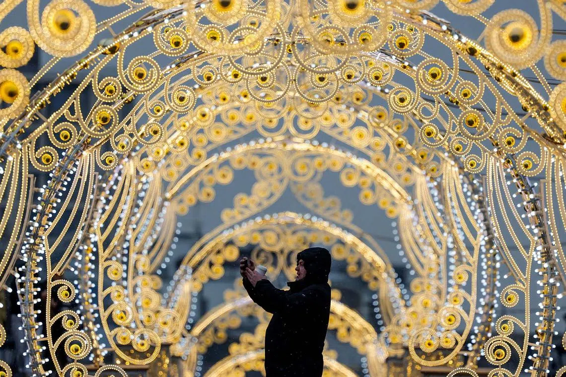 A man taking photos on his smartphone while standing next to street decorations in Moscow, Russia, Feb 13, 2025. 