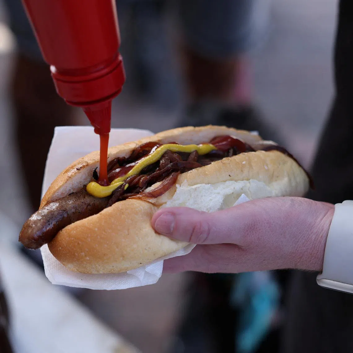 A voter puts ketchup on a so-called \"democracy sausage\" on the day of the Australian federal election, in Sydney, Australia, May 3, 2025. REUTERS/Hollie Adams