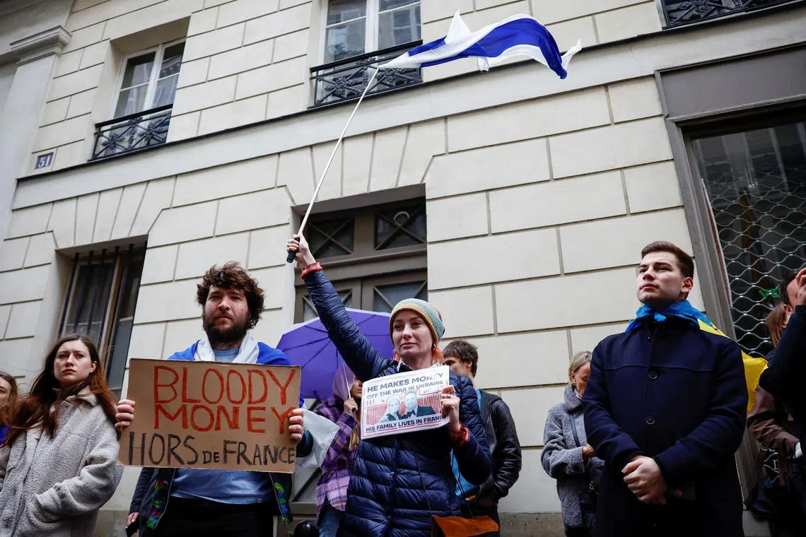 Protesters attend a demonstration outside the home of Svetlana Maniovich, the wife of the Russian Deputy Minister of Defence, to call upon French authorities to expel her, with a placard that reads "Bloody money out of France" in Paris, France, April 23, 2023. REUTERS/Sarah Meyssonnier