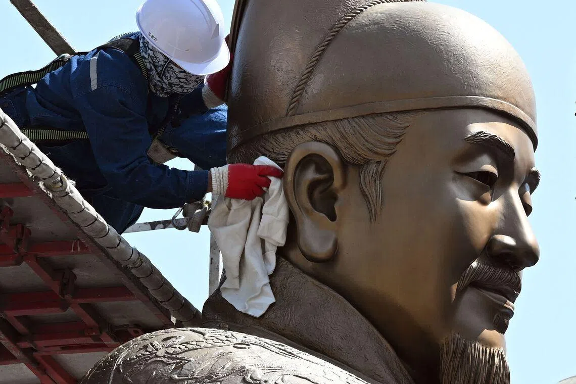 TOPSHOT - A worker wipes the bronze statue of King Sejong, the 15th century Korean king, during a spring cleaning event at Gwanghwamun Square in Seoul on April 13, 2026. (Photo by Jung Yeon-je / AFP)