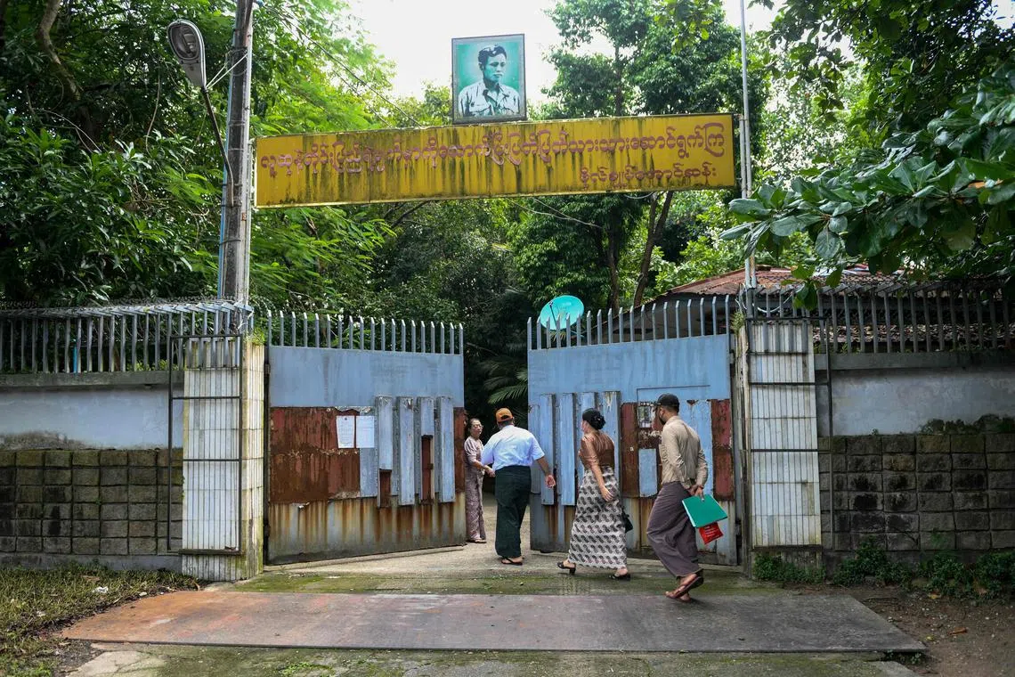 Auction officials walk through the gates of the family house of Ms Aung San Suu Kyi in Yangon.