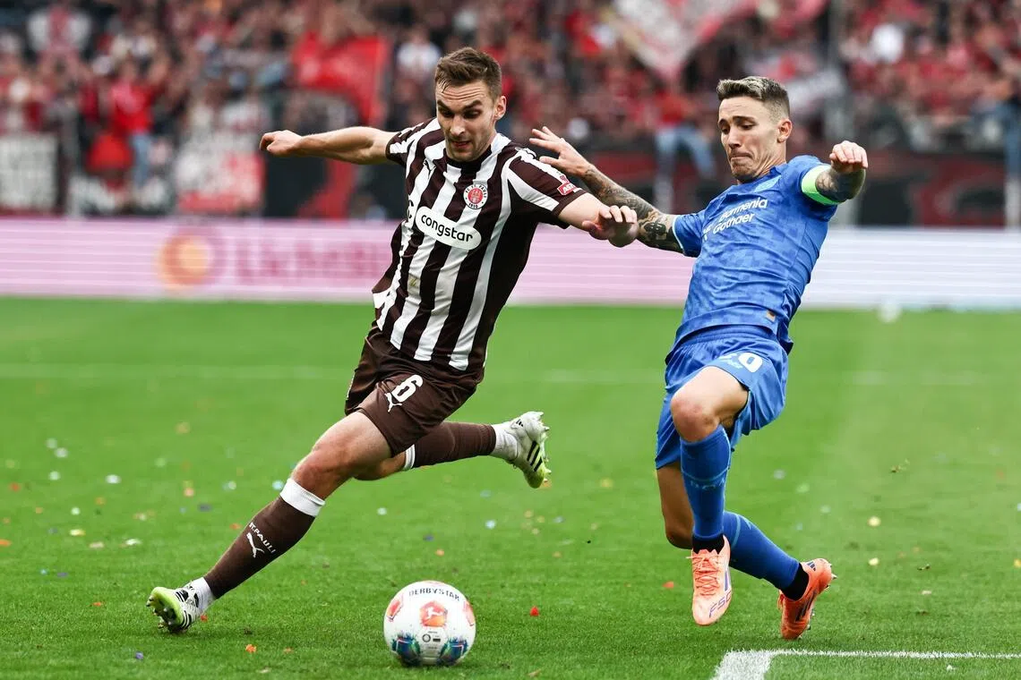 Alejandro Grimaldo (right) of Leverkusen trying to get past James Sands of St Pauli in their German Bundesliga match in Hamburg on Sept 27, 2025.