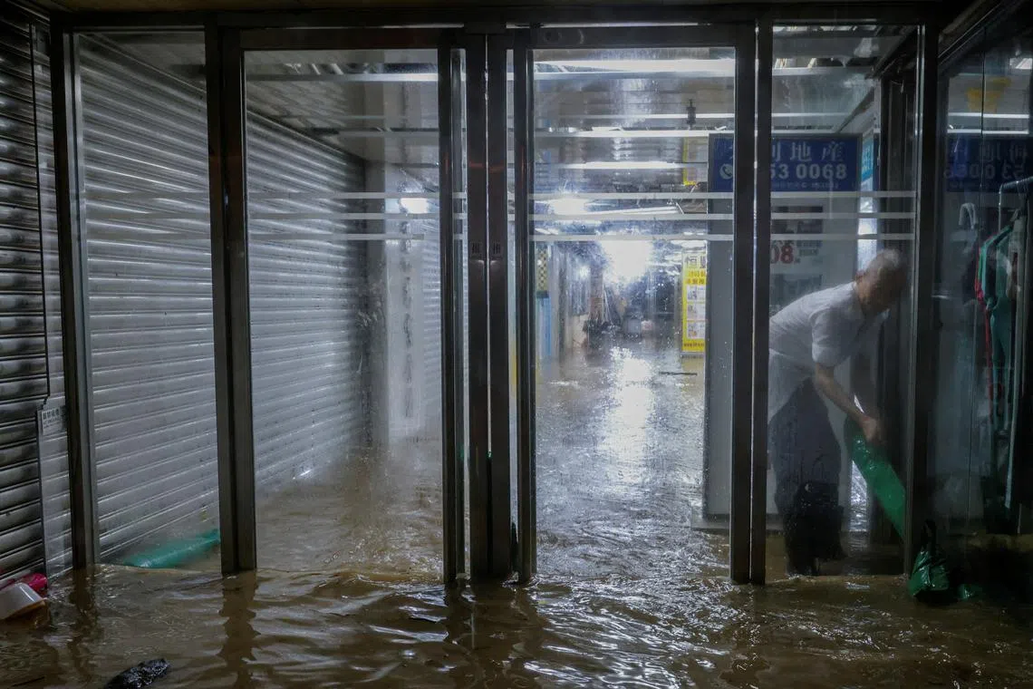 A shopping mall worker places sandbags to block water during heavy rain in Hong Kong, China, Sept 8, 2023. 