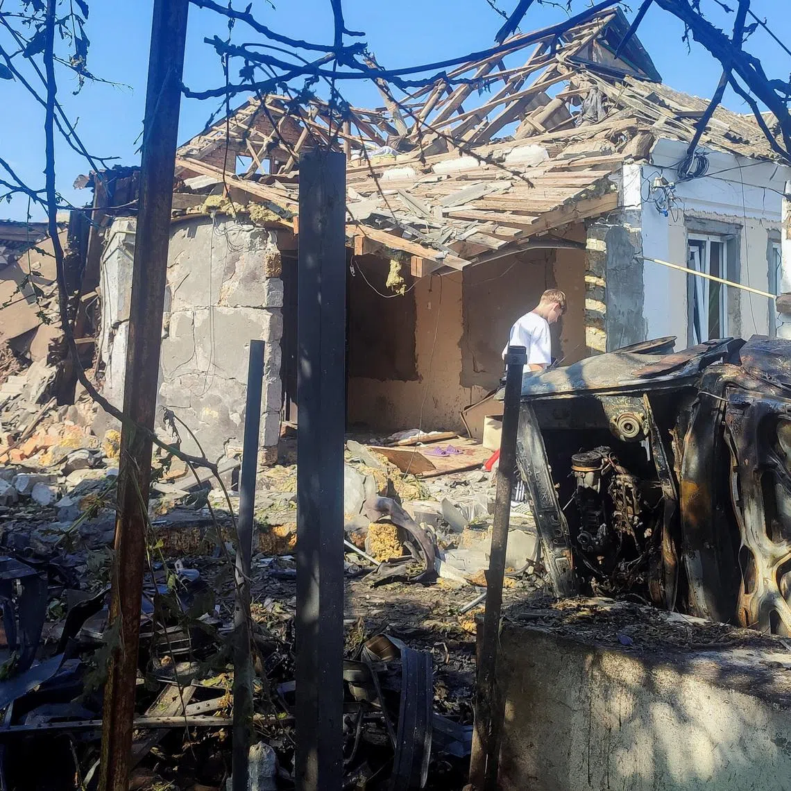 A resident stands at a site where a house was heavily damaged by a Russian drone strike, amid Russia's attack on Ukraine, in Mykolaiv, Ukraine June 12, 2026. Picture taken with a mobile phone. REUTERS/Viktoriia Lakezina