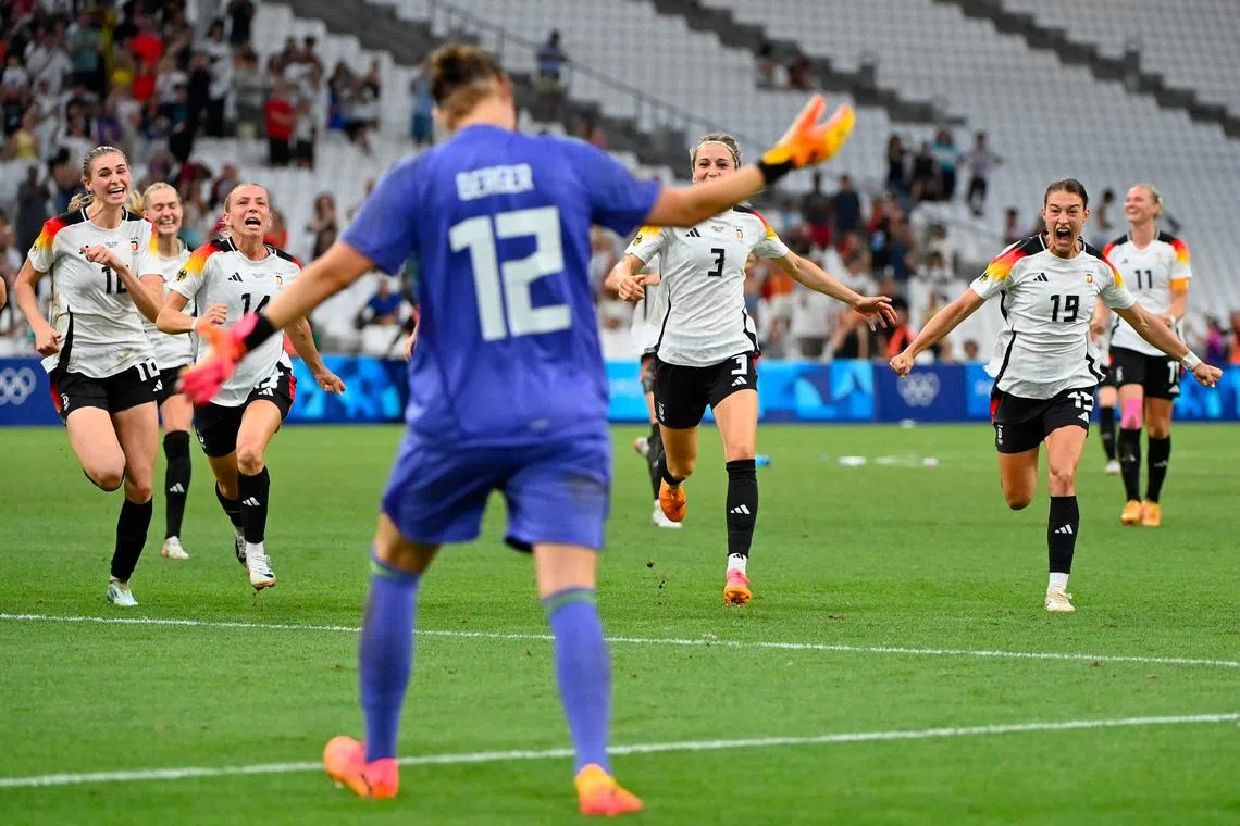 Germany's players run to celebrate their victory with goalkeeper Ann-Katrin Berger after the penalty shootout in their women's quarter-final football match against Canada.