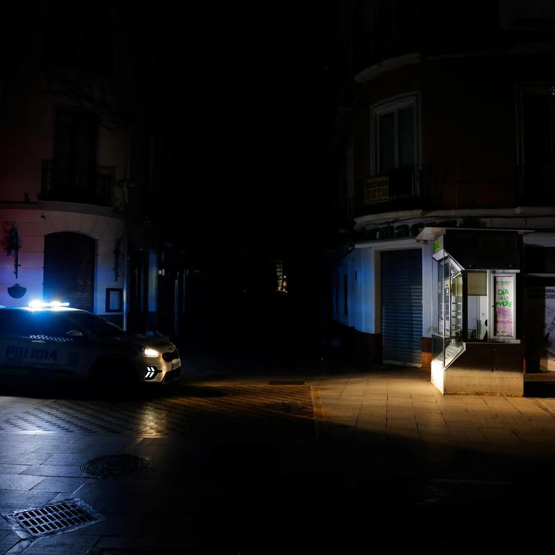 A local police car patrols a shopping street without electric lighting to prevent theft and looting in the stores in the early morning hours during a power outage which hit large parts of Spain, in Ronda, Spain April 29, 2025. REUTERS/Jon Nazca