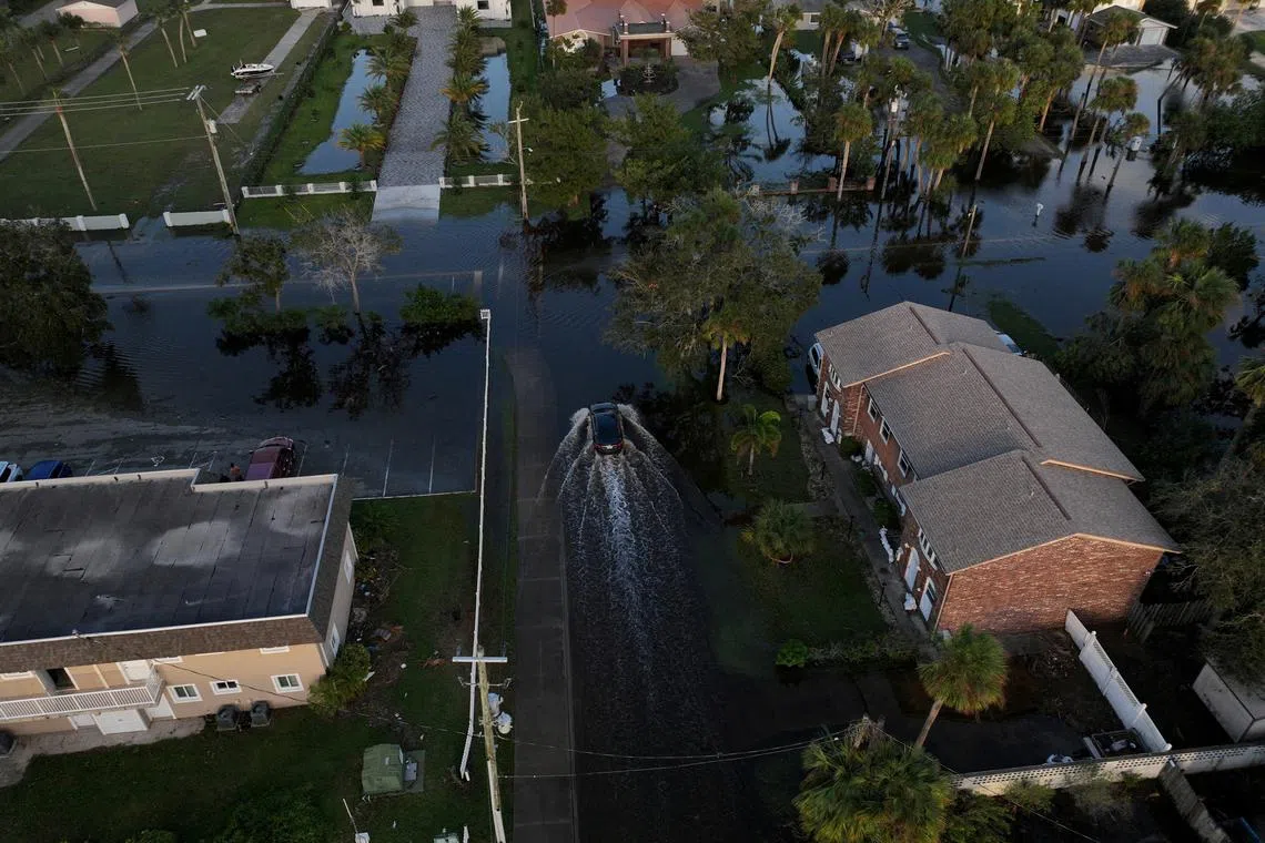 FILE PHOTO: A drone view shows a car driving through a flooded street after Hurricane Milton made landfall in South Daytona, Florida, U.S., October 11, 2024. REUTERS/Ricardo Arduengo/File Photo