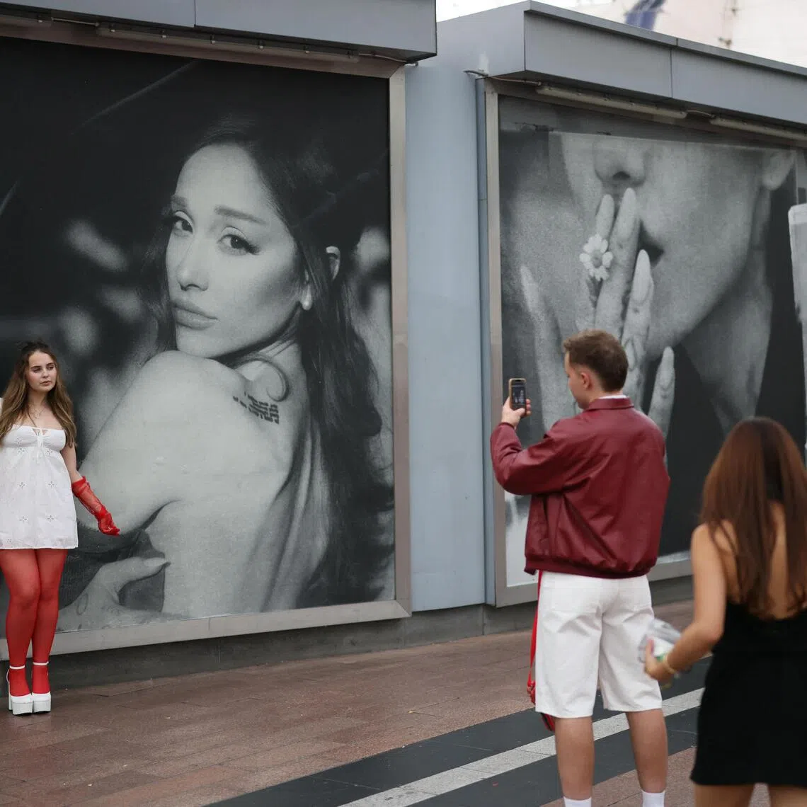 Ariana Grande fans take pictures in front of a billboard as they gather ahead of the opening night of the London leg of the actress and singer's The Eternal Sunshine Tour, in London, Britain, August 15, 2026. REUTERS/Jack Taylor
