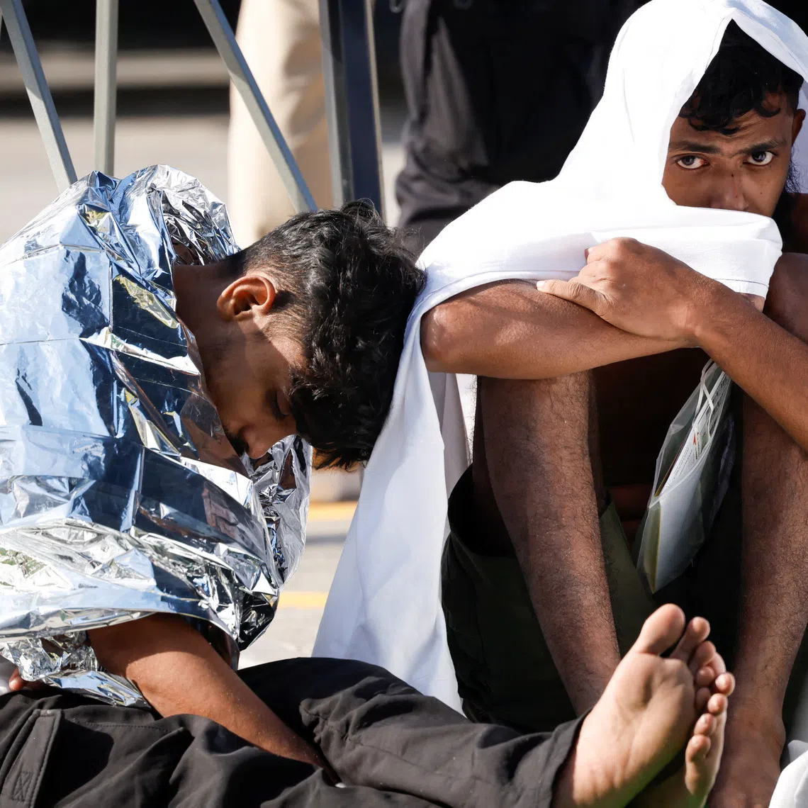 Migrants sit on the ground after a group of some 60 migrants was brought to Malta after their boat capsized close to the Mediterranean island, in Bugibba, Malta, December 12, 2025. REUTERS/Darrin Zammit Lupi