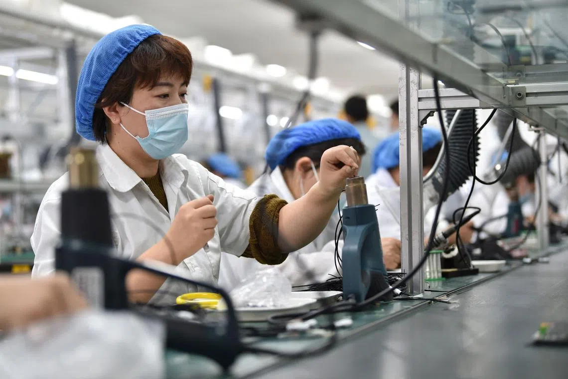 Workers produce vibratory feeder controllers at a factory in Nanjing, China, on Oct 24, 2022.
