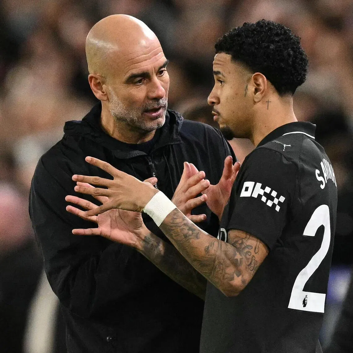 Manchester City manager Pep Guardiola speaks with Savinho during the Premier League match against Leeds United.