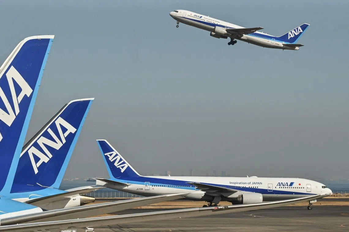 This photo taken on January 30, 2024 shows a Japanese airline All Nippon Airways (ANA) passenger plane (top) taking off as another (R) taxis past others parked at the gates at Tokyo International Airport at Haneda in Tokyo. (Photo by Richard A. Brooks / AFP)