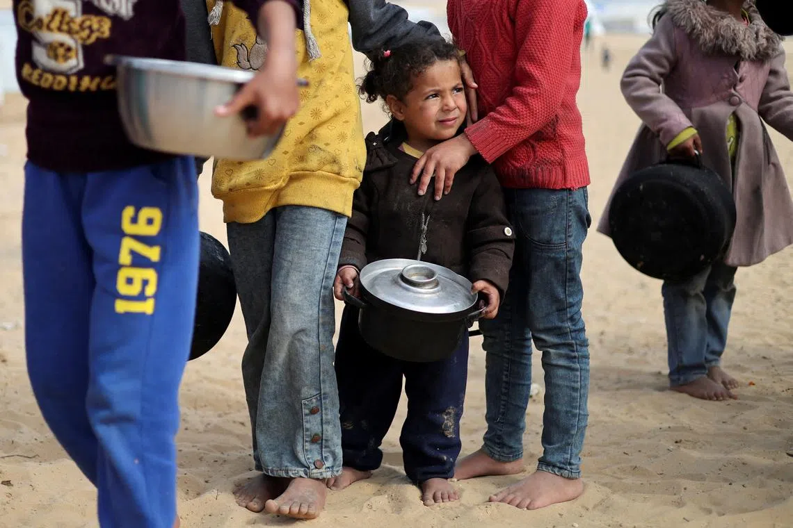 FILE PHOTO: Displaced Palestinian children wait to receive free food at a tent camp, amid food shortages, as the conflict between Israel and Hamas continues, in Rafah in the southern Gaza Strip, February 27, 2024. REUTERS/Ibraheem Abu Mustafa/File Photo