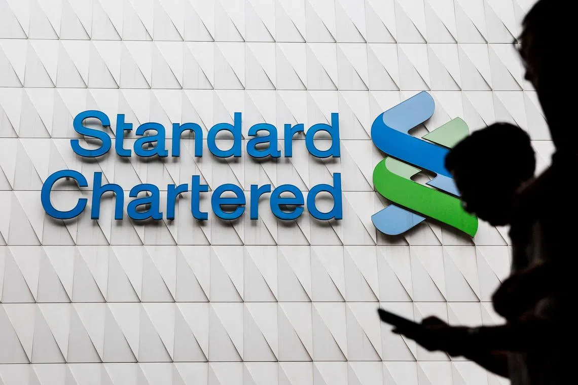 (FILES) Pedestrians walk past Standard Chartered signage in the Central district of Hong Kong on August 2, 2017. Asia-focused British bank Standard Chartered revealed Thursday, October 26, that it sank into the red in the third quarter on vast China-linked charges, sending its share price tumbling. (Photo by Isaac LAWRENCE / AFP)