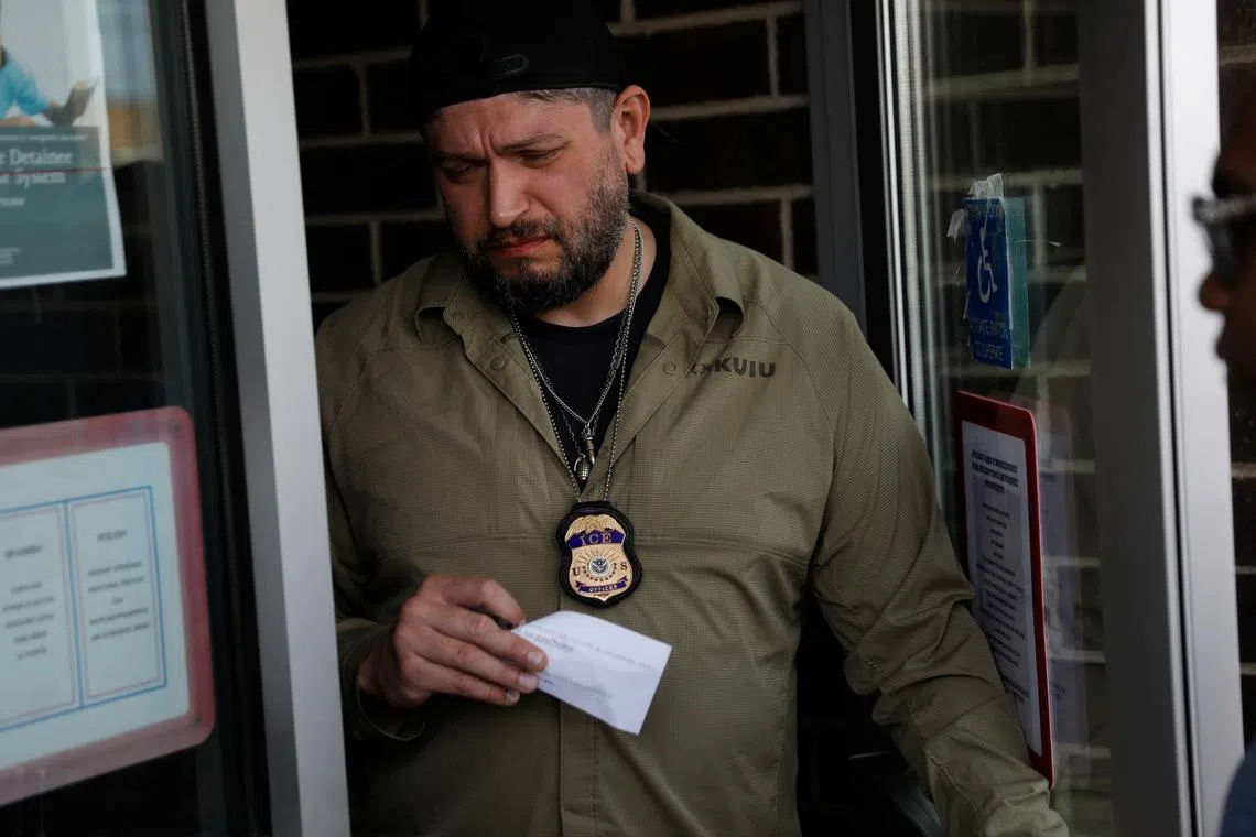 FILE PHOTO: An ICE agent talks with migrants about their scheduled appointments with U.S. Immigration and Customs Enforcement (ICE) on Father’s Day, to learn about their immigration status, in Chicago, Illinois., U.S., June 15, 2025. REUTERS/Octavio Jones/File Photo
