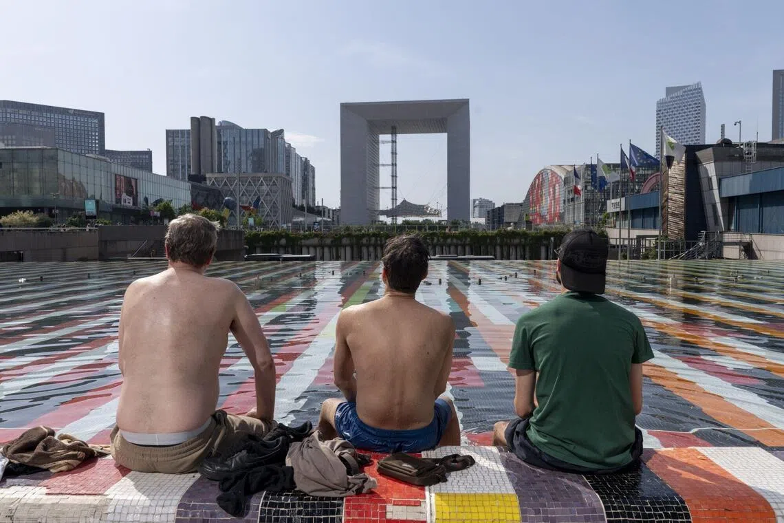 Workers cool themselves amid scorching heat at Fontaine d'Agam at the La Defense business district in Paris.
