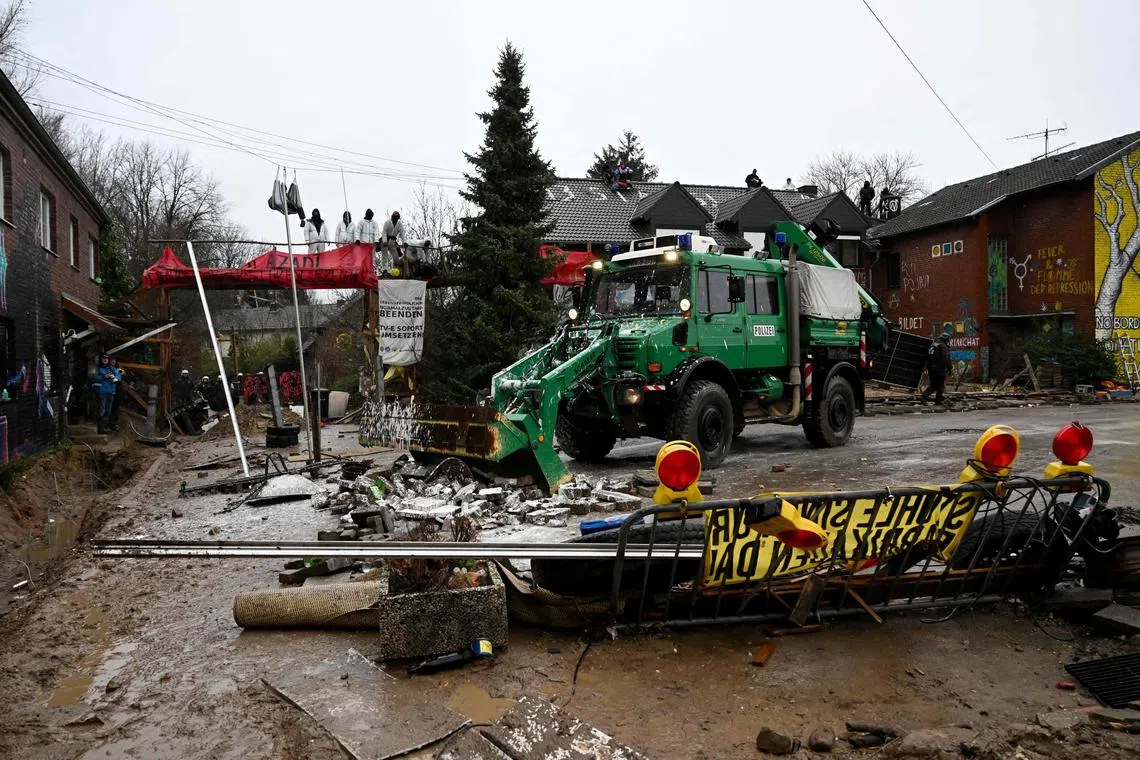Police remove barricades and debris in front of houses occupied by the environmentalists.