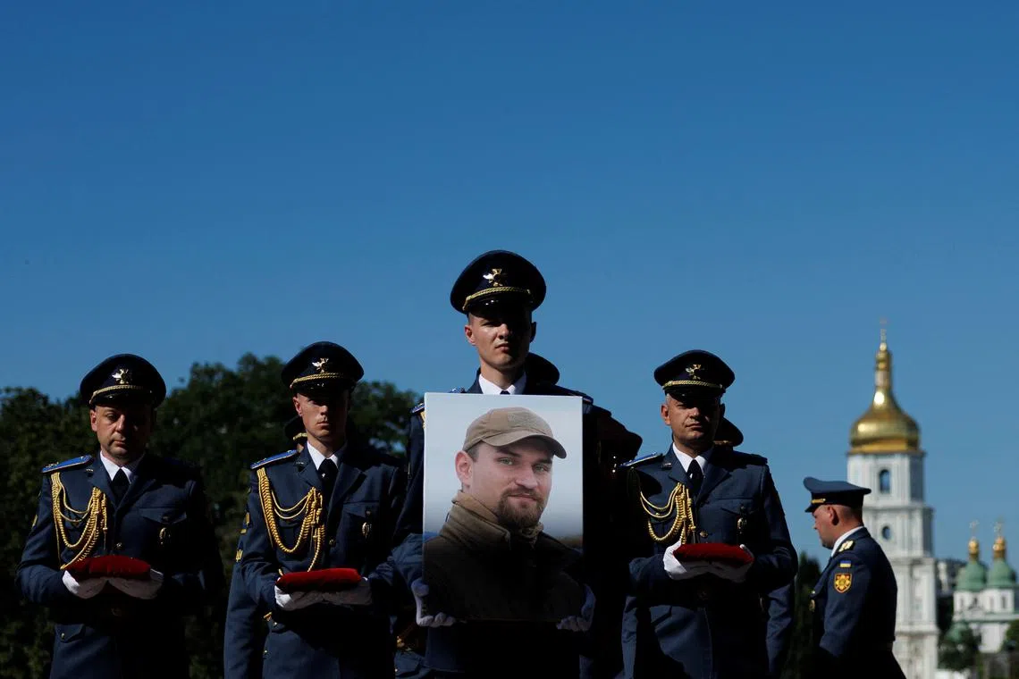 Service members of Honour Guard carry a portrait of Ukrainian military pilot Colonel Maksym Ustymenko, who died last Sunday operating an F16 fighter jet during a combat mission, amid Russia's attack on Ukraine, during his funeral ceremony in Kyiv, Ukraine July 3, 2025.  REUTERS/Valentyn Ogirenko