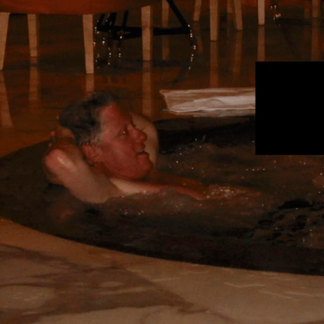 Bill Clinton in a hot tub with an unknown person, in an undated photo redacted and released by the US Department of Justice on Dec 19, 2025. 