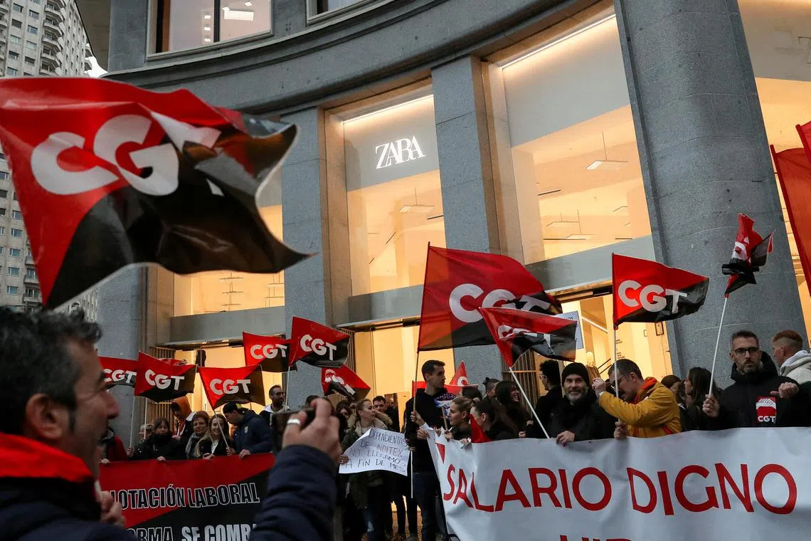 A file photo of people holding flags from Spain's CGT labour union as they protest outside a Zara clothing store, an Inditex brand, for an increase in salaries amid inflation hikes in Madrid, Spain, on Nov 24, 2022.