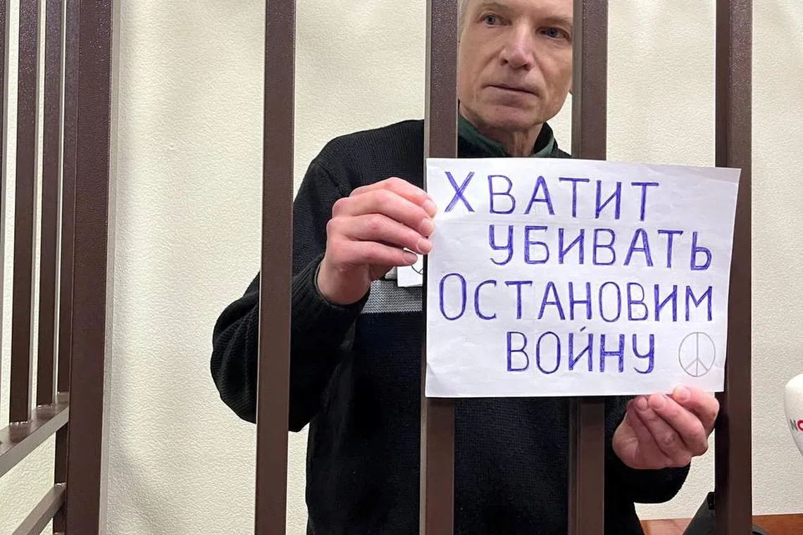 Moscow city councillor Alexei Gorinov, serving a seven-year sentence for criticising Russia's invasion of Ukraine, holds a placard reading \"Stop killing. Let's stop the war\" as he stands inside a defendants' cage during a new court hearing against him for \"justifying terrorism\", in Vladimir, Russia, November 27, 2024.  Social Media/via REUTERS
