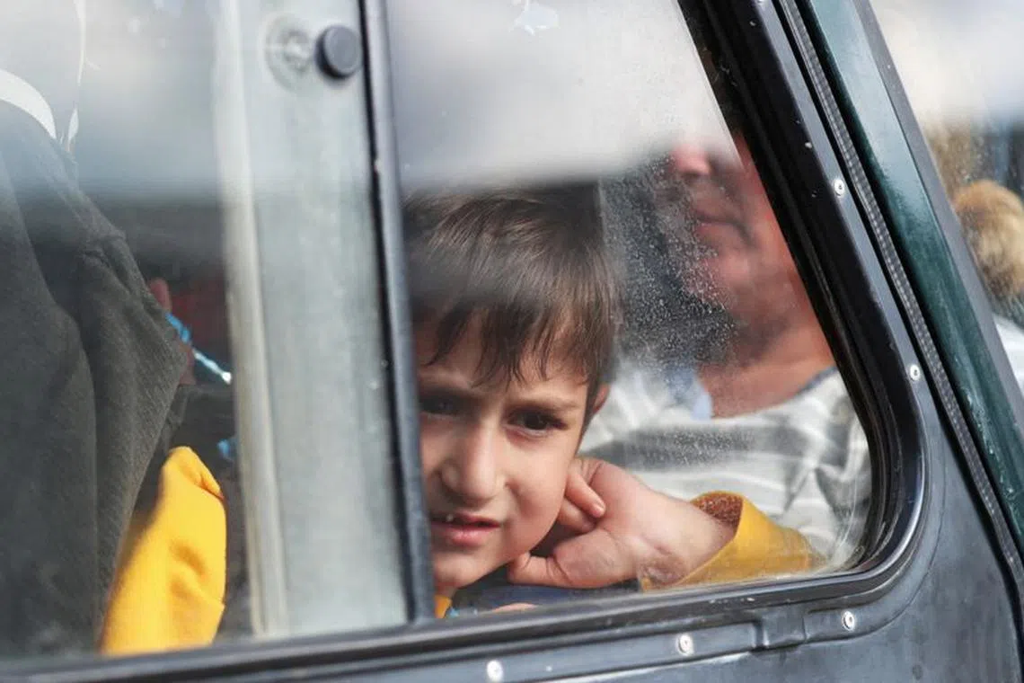 A refugee boy from Nagorno-Karabakh region looks out of a car window upon arrival at a temporary accommodation centre in the town of Goris, Armenia, September 25, 2023. REUTERS/Irakli Gedenidze