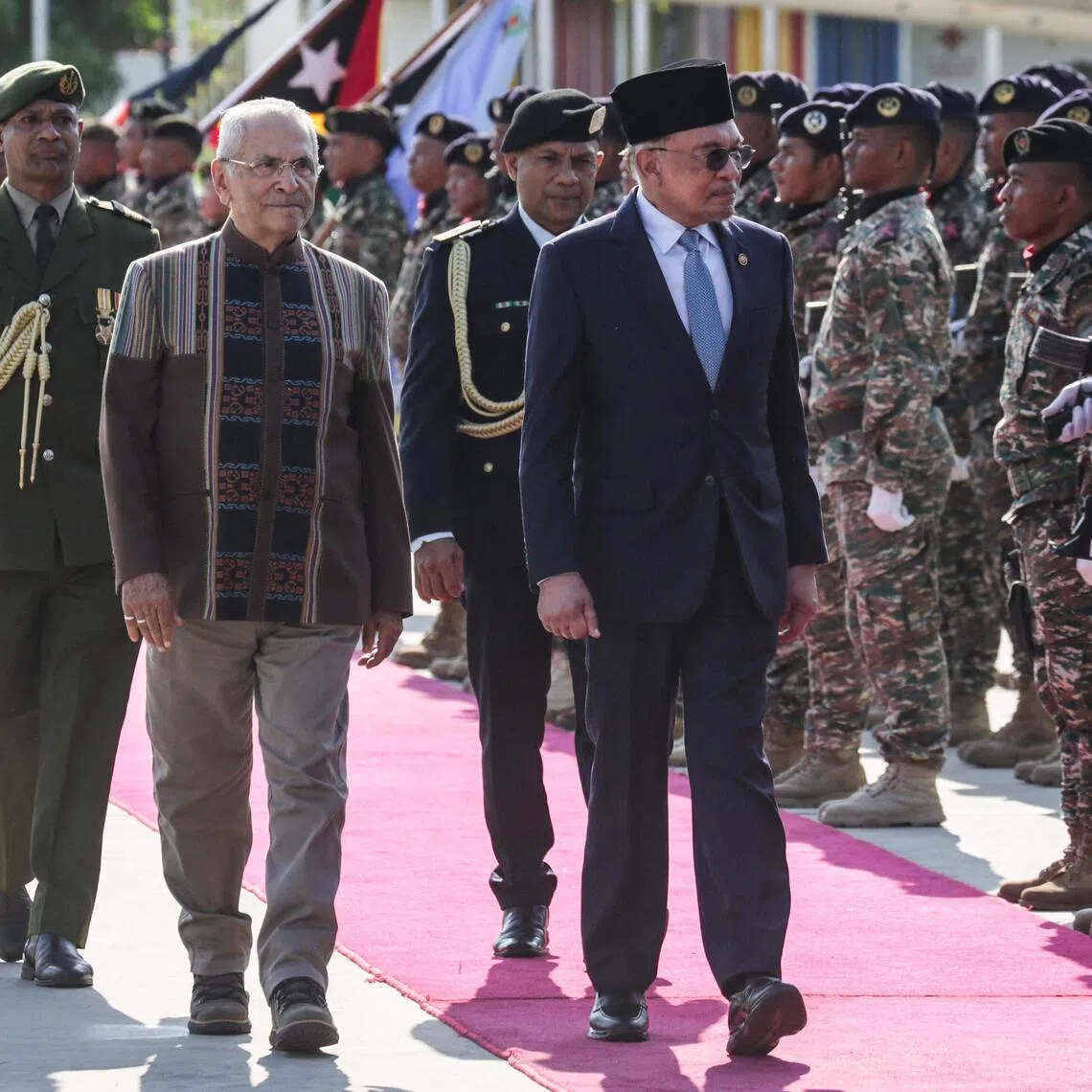 Malaysia's Prime Minister Anwar Ibrahim (R) and East Timor's President Jose Ramos-Horta (2nd L) inspect the guard of honour at the Presidential Palace in Dili, East Timor, on September 23, 2025. (Photo by Valentino Dariell DE SOUSA / AFP)