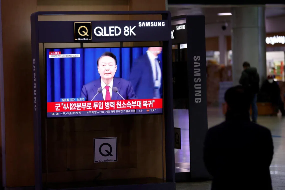A person watches a TV screen broadcasting a news report on South Korean President Yoon Suk Yeol's declaration of martial law and the following announcement that he will lift the martial law, after parliamentary vote, at a railway station in Seoul, South Korea, December 4, 2024. REUTERS/Kim Soo-hyeon