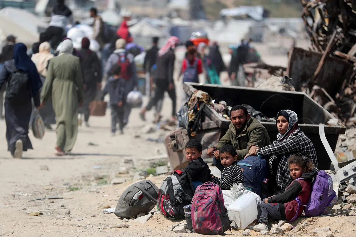 People sit as Palestinians make their way to flee their homes, after the Israeli army issued evacuation orders for a number of neighborhoods, following heavy Israeli strikes, in the northern Gaza Strip March 18, 2025. REUTERS/Mahmoud Issa