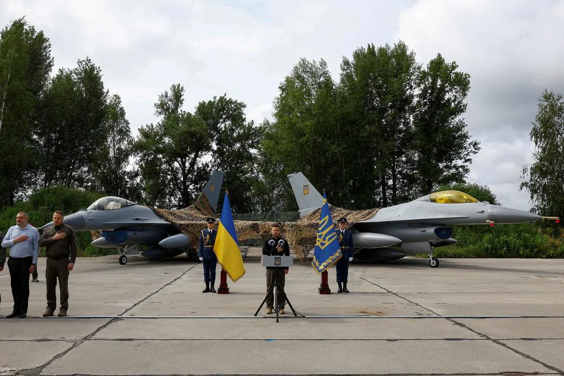 FILE PHOTO: Ukraine's President Volodymyr Zelenskiy sings a national anthem next to F-16 fighting aircrafts during marking the Day of the Ukrainian Air Forces, amid Russia's attack on Ukraine, in an undisclosed location, Ukraine August 4, 2024. REUTERS/Valentyn Ogirenko/File Photo