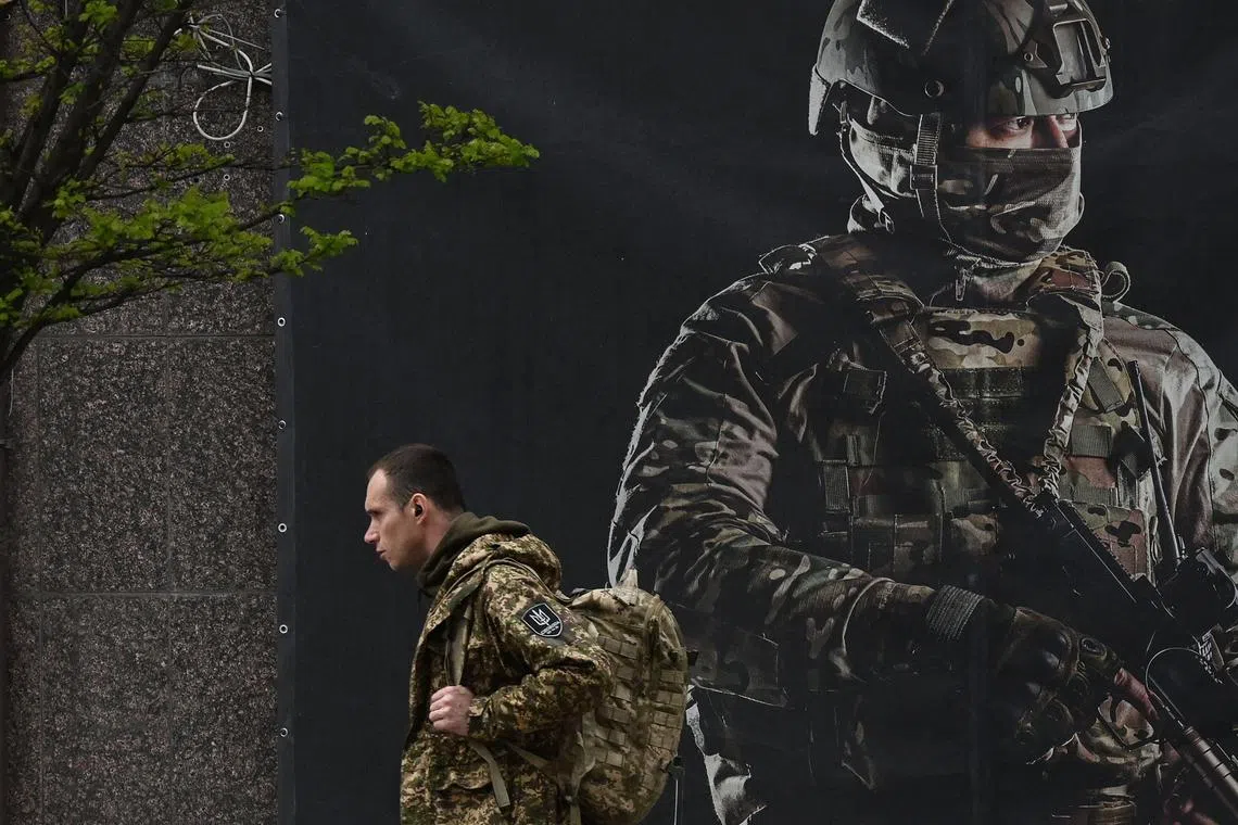 A Ukrainian serviceman walks past a recruiting poster in Kyiv on April 23 amid the Russian invasion of Ukraine. 