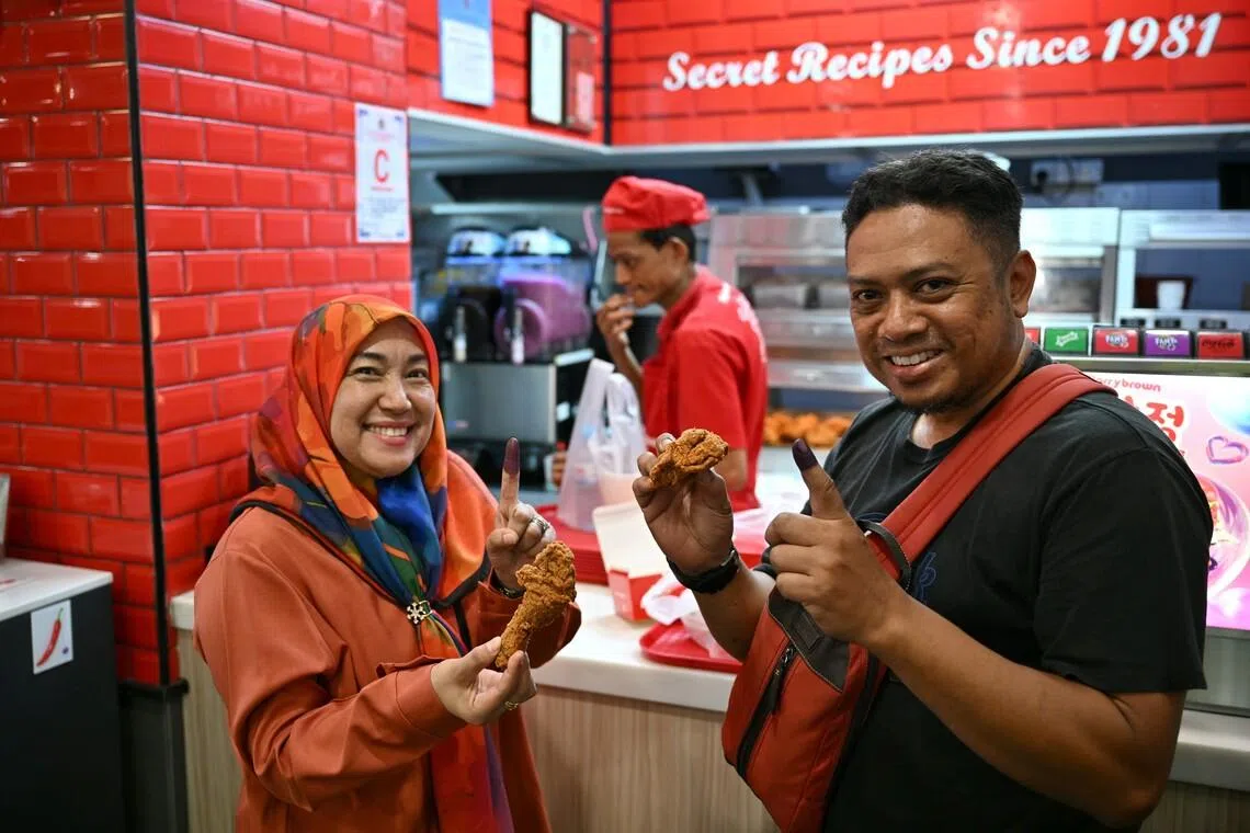 BN supporters Nur Azan Ismail and his wife, Faizah Hashim seen at a Marrybrown outlet in Larkin Sentral collecting free chicken after voting on July 11.