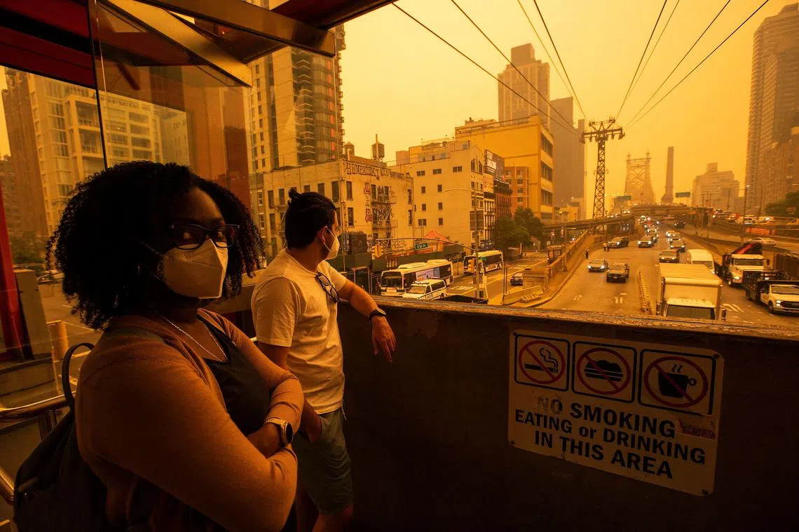 People wearing masks as they wait for the tramway to Roosevelt Island as smoke from Canadian wildfires casts a haze over the area on June 7, 2023 in New York City. 