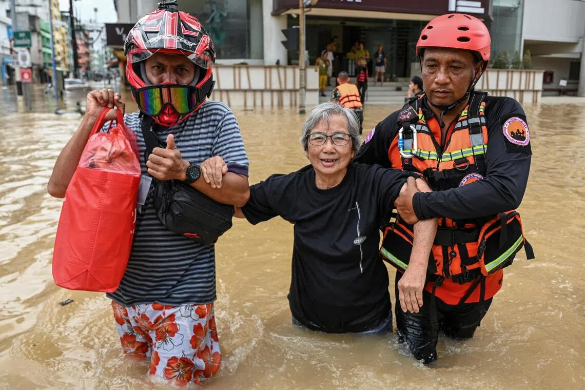 Rescuers evacuate a tourist from a hotel through a flooded street in Hat Yai district.