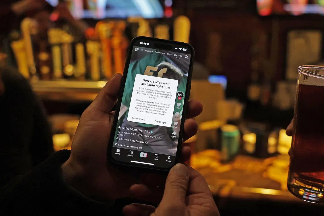 A TikTok user holds a phone showing the screen of the social media app on Jan 18.